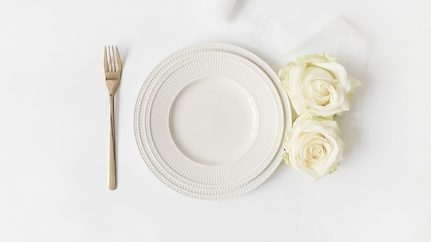 Fourchette; plaque de céramique; roses et ruban de satin sur fond blanc Photo gratuit