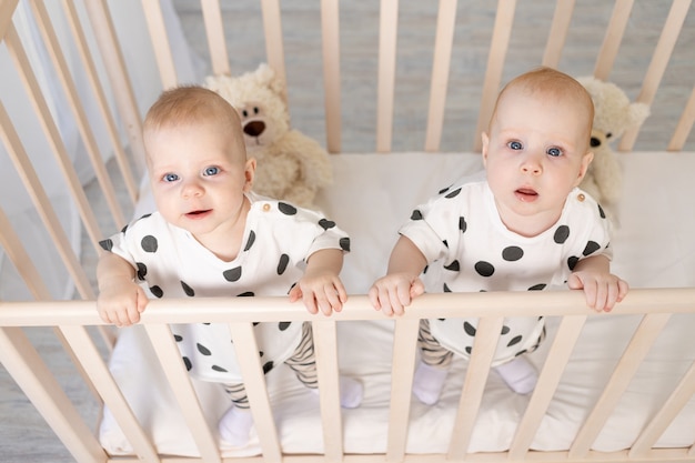 Frere Et Soeur Jumeaux Bebe Assis En Pyjama Dans Le Berceau Photo Premium