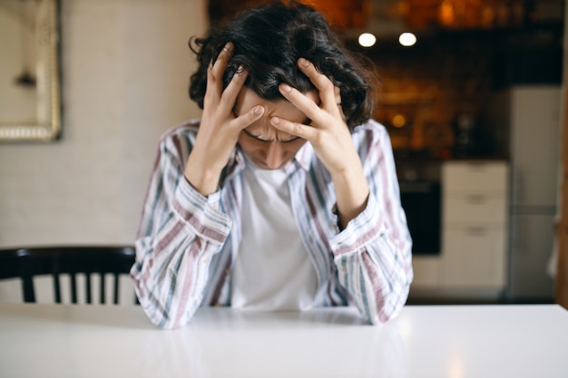 Frustré Malheureux Jeune Homme Ayant Un Regard Déprimé Regardant Vers Le Bas Tenant Les Mains 