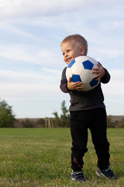 Un Gar on Heureux Tient Le Ballon Et Sourit Il  Est  Debout 