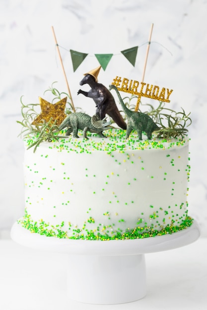 Gateau D Anniversaire Blanc Avec Decorations Vertes Etoile D Or Et Dinosaures Sur Un Support A Gateau Photo Premium