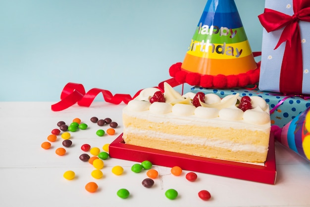 Gateau D Anniversaire Avec Des Bonbons Chapeau Et Presente Sur Table Sur Fond Bleu Photo Gratuite