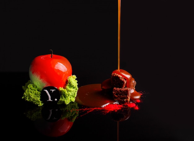 Gâteau au chocolat avec mousse au caramel dans le glaçage miroir. avec des noix. sur le fond noir réflexion. Photo Premium