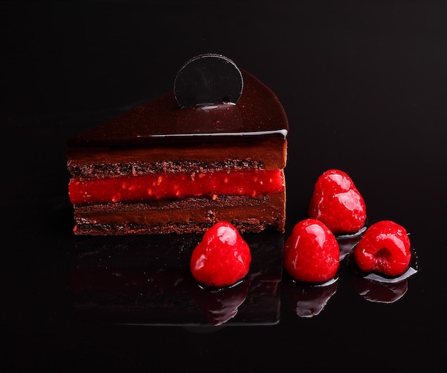 Gâteau au chocolat zacher à la framboise, mousse dans le reflet du miroir, section. sur le fond noir Photo Premium