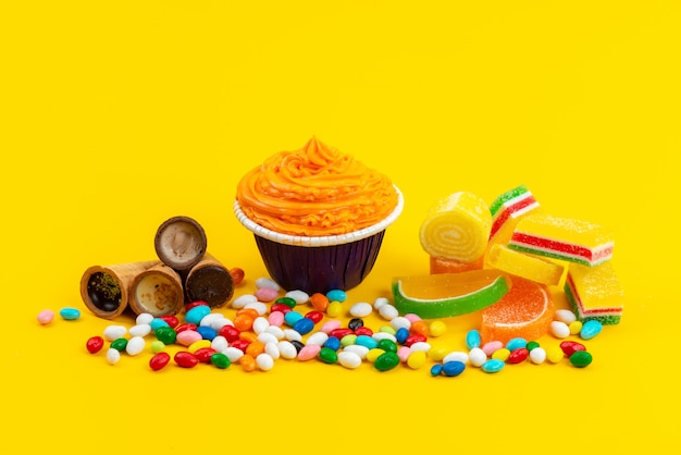 Un Gateau Et Des Bonbons Vue De Face Avec Des Cornes De Glace Et Des Friandises Sur Le Bureau Jaune Couleur Bonbon Photo Gratuite