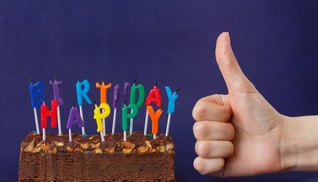 Gateau Brownie Joyeux Anniversaire Avec Des Arachides Du Caramel Sale Et Des Bougies Colorees Non Eclairees Sur La Surface Violette Montre A La Main Comme Photo Premium