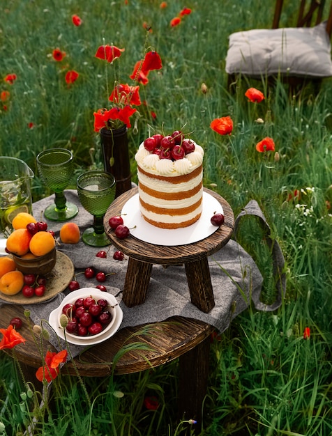 Gateau Eponge Aux Merries Sur La Table En Bois Dans Le Champ De Coquelicots Une Chaise En Bois Fait Partie De La Composition Photo Premium