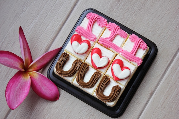 Gâteaux avec des coeurs de crème et une fleur de frangipanier. l'écriture je t'aime sur les gâteaux. Photo Premium