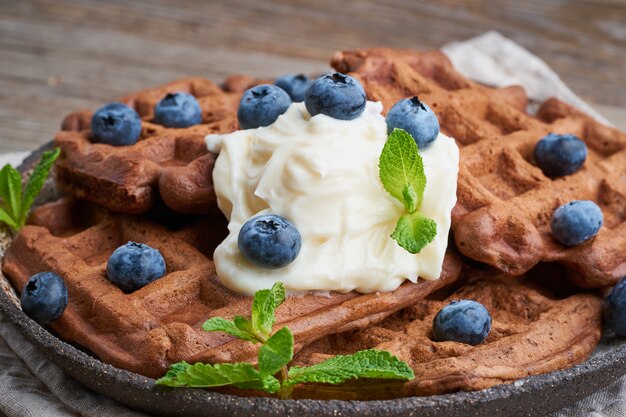 Gaufres Bananes Au Chocolat Avec Des Bleuets, Sur Une Vieille Table En Bois Sombre. Vue De Côté, Gros Plan Photo Premium