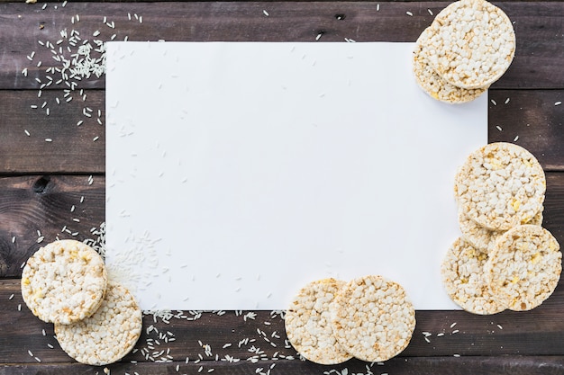 Grains De Riz Et Gateau De Riz Souffle Sur Du Papier Vierge Blanc Sur Le Bureau En Bois Photo Gratuite