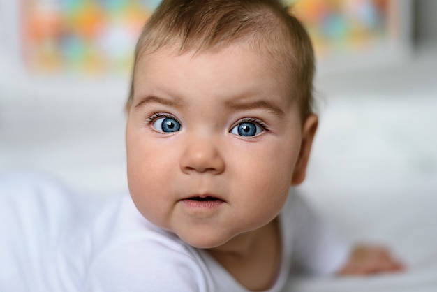 Gros Plan Bebe Aux Yeux Bleus En Body Blanc Sur Lit Blanc Photo Premium