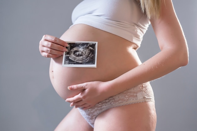 Gros Plan Du Ventre De Jeune Modele Grave Montrant L Image Ultrasonore De Son Bebe Future Maman Sur Son Deuxieme Trimestre Tenant L Echographie De Son Enfant Concept De Maternite Photo Gratuite