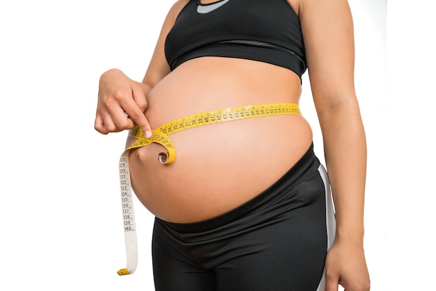 Gros Plan D Une Femme Enceinte A L Aide D Un Ruban A Mesurer Pour Verifier Le Developpement Du Bebe Concept De Grossesse Et De Maternite Photo Premium