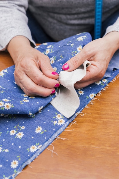 Gros plan, main, personne, coudre, tissu floral, à, aiguilles, bureau Photo gratuit