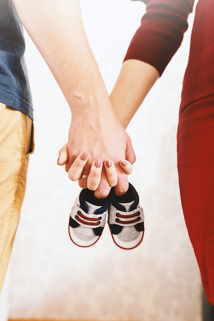 Gros Plan Des Parents Heureux En Attente De Bebe Et Se Tenant La Main Dans Les Mains Des Chaussures De Bebe Photo Premium