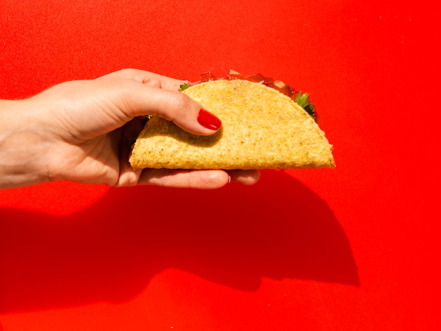 Gros plan personne avec taco et fond rouge Photo gratuit