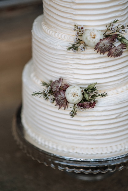 Gros Plan Vertical Tourne D Un Gateau De Mariage A Trois Couches Decore De Fleurs Sur Un Plateau D Argent Photo Gratuite