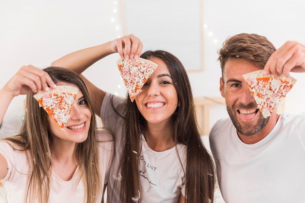 Groupe d'amis couvrant leurs yeux avec une tranche de pizza Photo gratuit