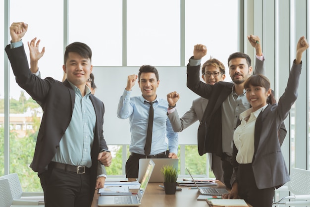 Groupe de collègues de travail gens d'affaires debout et mains levées ensemble prêts à travailler pour réussir Photo Premium