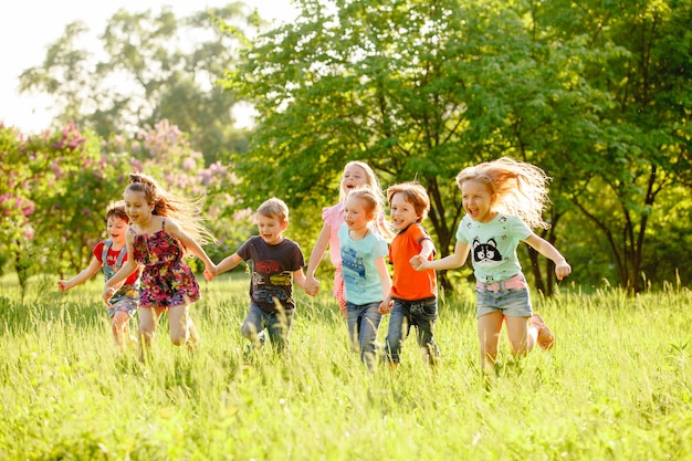 Un Groupe D enfants Heureux De Garçons Et De Filles Courent Dans Le Parc Sur L herbe Par Une