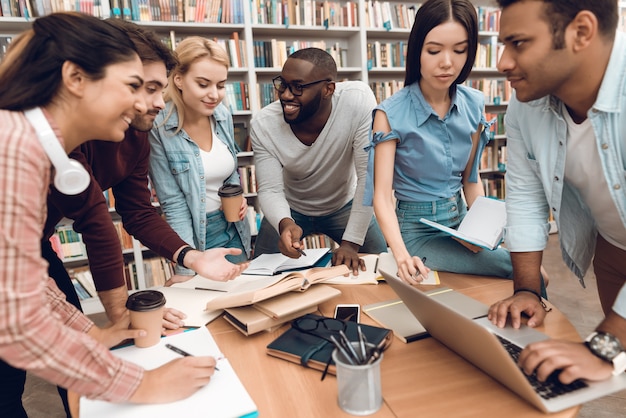 Groupe d'étudiants multiculturels ethniques discutant dans la bibliothèque Photo Premium