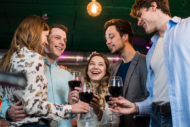 Groupe de joyeux amis profitant d'un verre en soirée au bar Photo gratuit