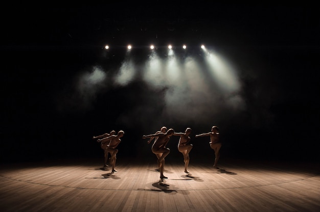 Un groupe de petits danseurs de ballet répète sur scène avec lumière et fumée Photo Premium