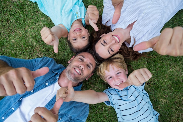 Heureuse famille dans le parc ensemble pouce en l'air par une journée ensoleillée Photo Premium
