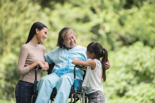 Heureuse grand-mère en fauteuil roulant avec sa fille et son petit-fils dans un parc, happy life happy time. Photo gratuit