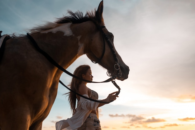 Heureuse Jeune Femme A La Mode Qui Pose Avec Un Cheval Sur La Plage Photo Premium