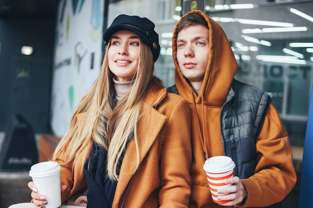 Heureux jeune couple amoureux amis adolescents habillés dans un style décontracté avec café pour aller marcher ensemble dans la rue en saison froide Photo Premium