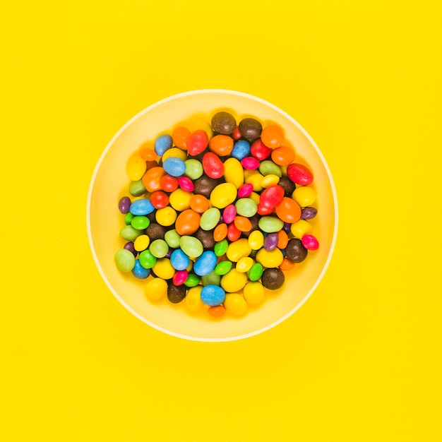 High angle de vue de bonbons colorés sur une plaque sur une surface jaune Photo gratuit