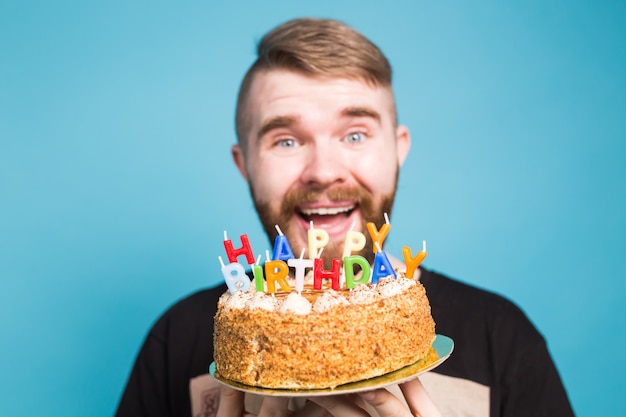 Hipster Drole De Gars Positif Fou Tenant Un Gateau De Joyeux Anniversaire Dans Ses Mains Debout Sur Un Mur Bleu Photo Premium