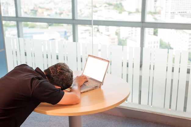 Homme d'affaire. faire une sieste, fatigué du travail, dormir devant un ordinateur portable, allongé sur ses mains. Photo Premium