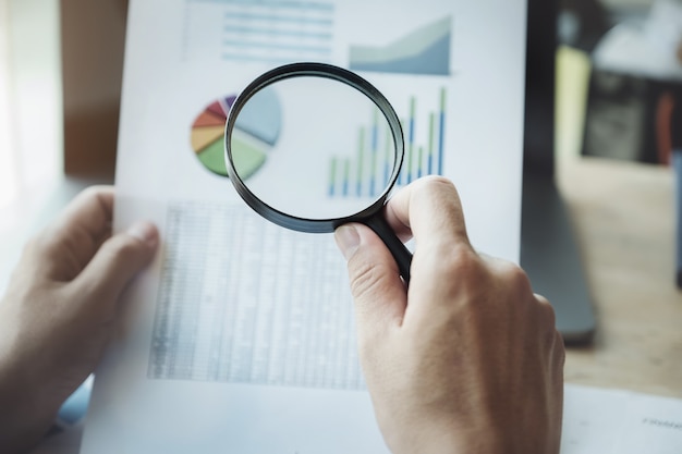 Homme d'affaires à l'aide de la loupe pour examiner le bilan annuel avec l'utilisation d'un ordinateur portable pour calculer le budget. audit et vérification de l'intégrité avant le concept d'investissement. Photo Premium