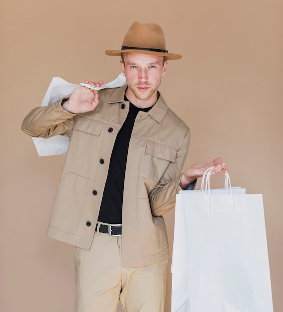 Homme au chapeau marron tenant les sacs à provisions Photo gratuit