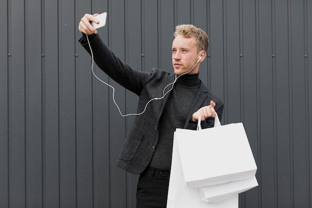  Homme  blond en noir  prenant un selfie  avec smartphone 