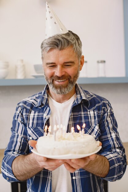 L Homme Dans Un Chapeau De Fete Garde Un Gateau Avec Des Bougies L Homme Porte Une Chemise Photo Gratuite