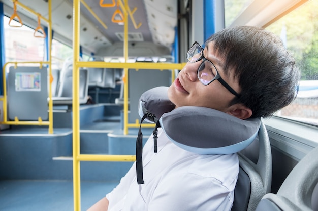 Homme fatigué dans l'autobus et dormir avec un oreiller gonflable cervical, transport Photo Premium