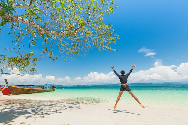 Homme heureux sur la plage de sable blanc et bateau à queue longue sur l'île de khang khao (bat island), dans la magnifique mer de la province de ranong, thaïlande. Photo Premium