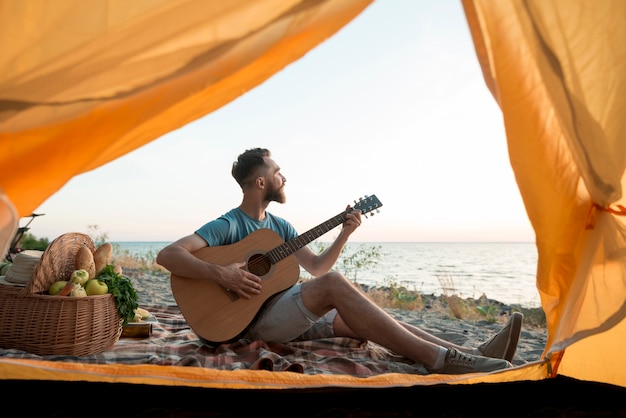 Homme Jouant De La Guitare Devant La Tente Photo Gratuite 