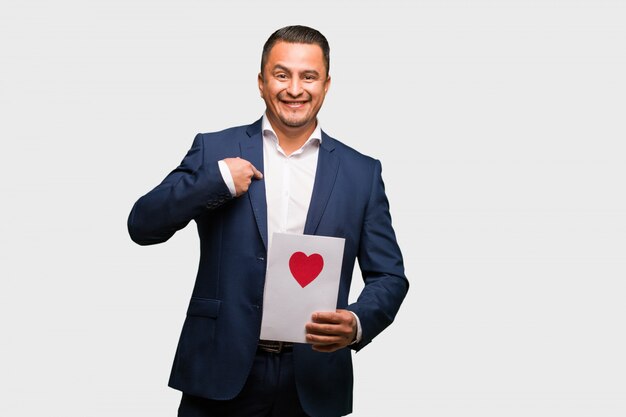 Homme latin d'âge moyen célébrant la saint valentin surpris, se sent réussi et prospère Photo Premium