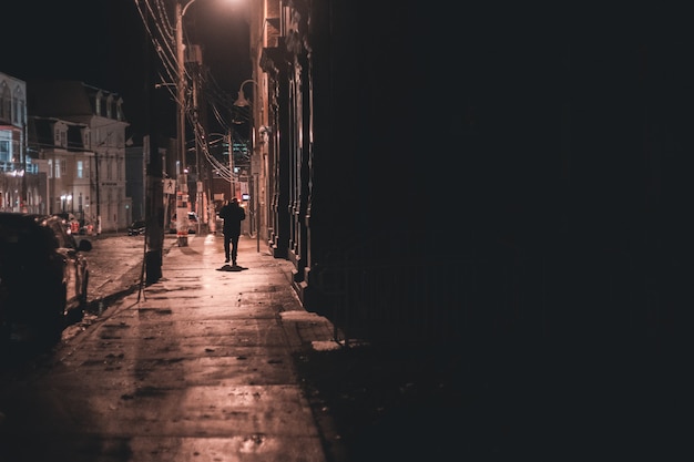 Homme Marchant Sur Le Trottoir Pendant La Nuit Photo Gratuite