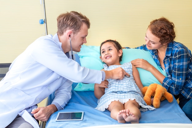 Homme De Pédiatre (médecin) Examine Le Patient De Petite Fille à L'aide D'un Stéthoscope Sur L'hôpital De La Chambre à Coucher. Photo Premium