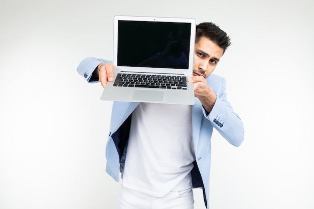 Homme Reussi Elegant Dans Une Veste Montre Un Ecran D Ordinateur Portable Avec Un Espace Pour La Publicite Sur Un Fond De Studio Blanc Photo Premium