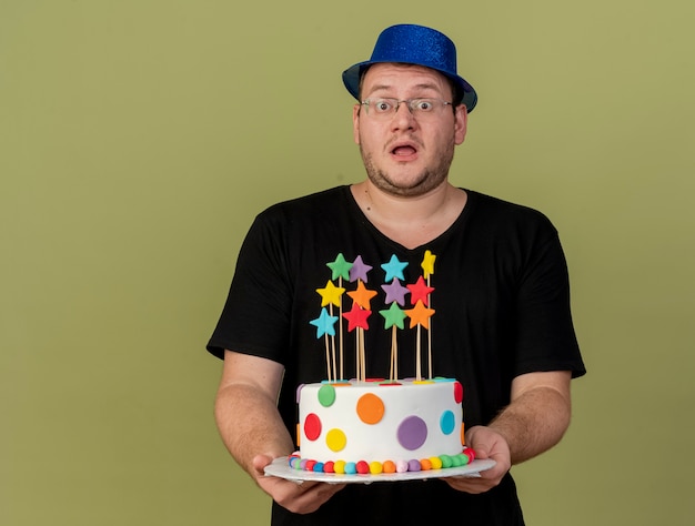 Un Homme Slave Adulte Impressionne Dans Des Lunettes Optiques Portant Un Chapeau De Fete Bleu Tient Un Gateau D Anniversaire Photo Gratuite