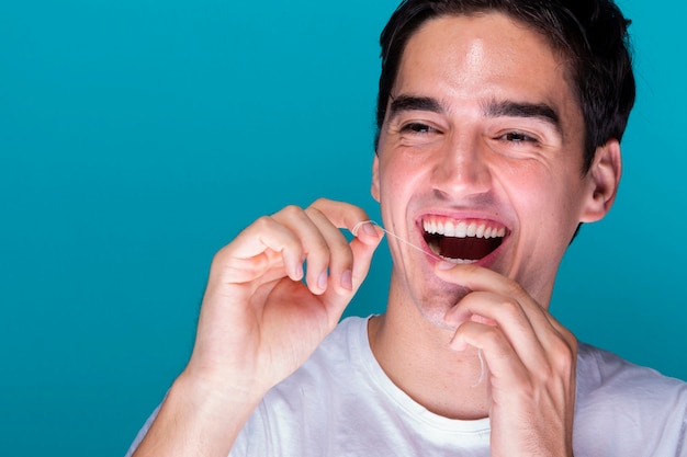Homme souriant, passant la soie dentaire Photo gratuit