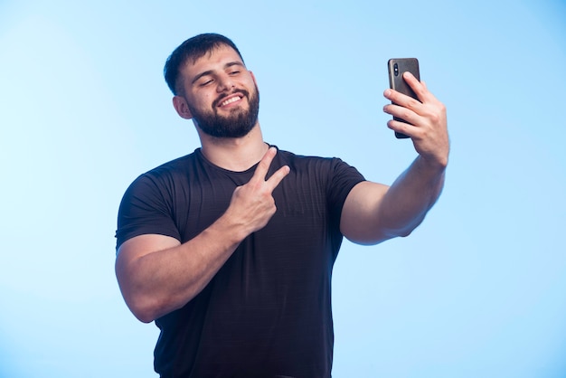  Homme  Sportif En Chemise Noire  Tient Le T l phone Et Prend 