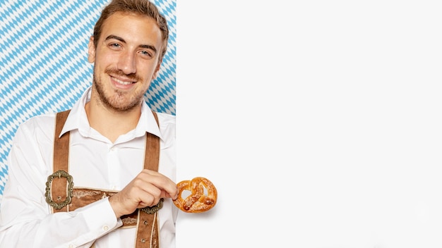 Homme tenant un bretzel avec maquette de signe Photo gratuit