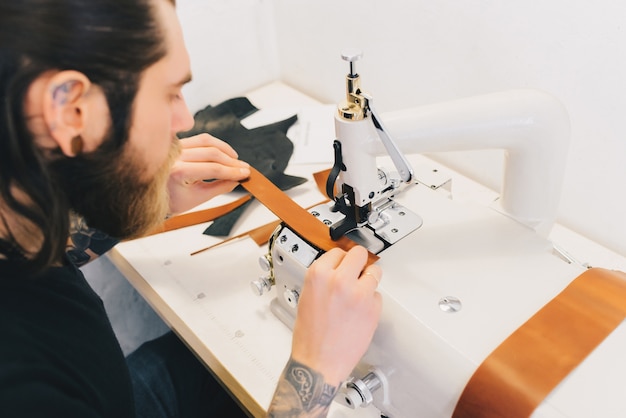 Homme travaillant avec le cuir traite le cuir avec une machine spéciale Photo gratuit